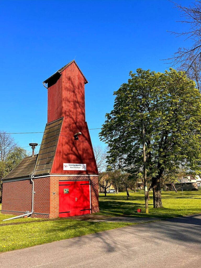 Ein rotes Feuerwehrgebäude mit einem kleinem Turm zum trocknen von Schläuchen.